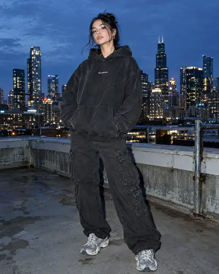 Woman in a black hoodie on a city rooftop at blue hour